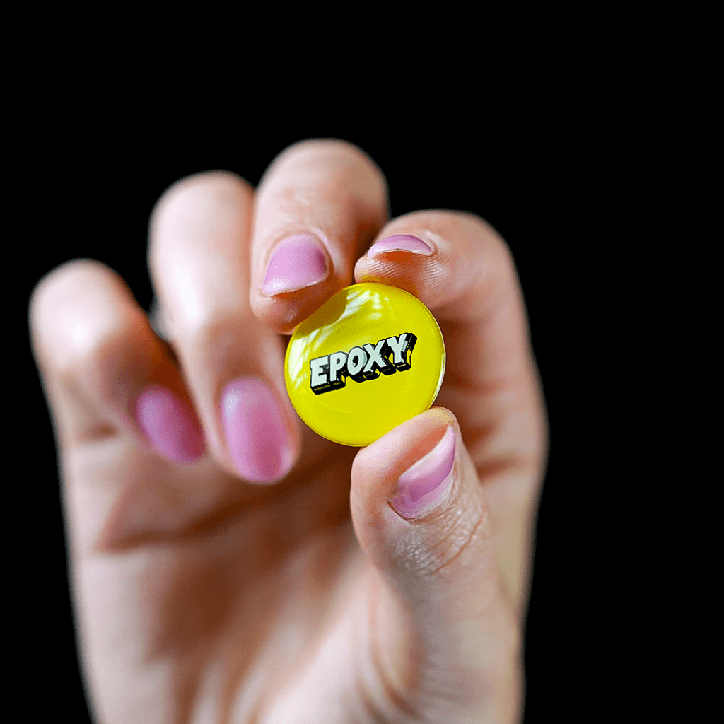 A person holding a Epoxy dome sticker with the word epox on it