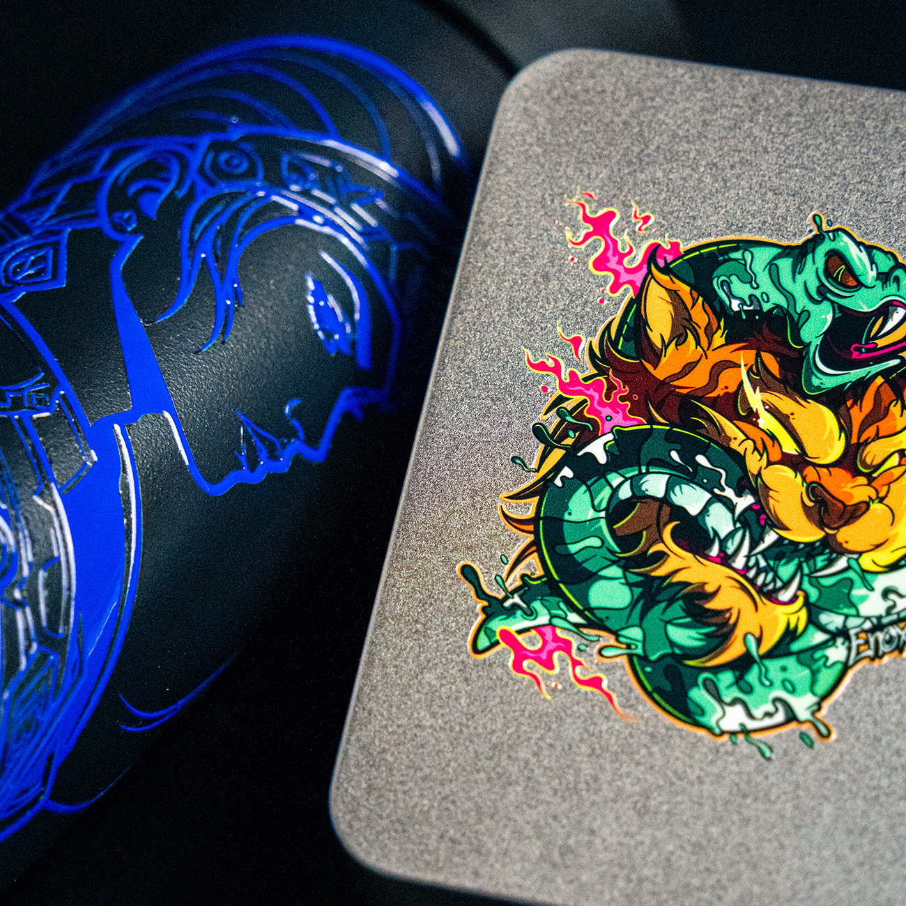 Vibrant, colorful transfer stickers featuring a stylized creature on a textured surface, next to a dark object with a glowing blue design.