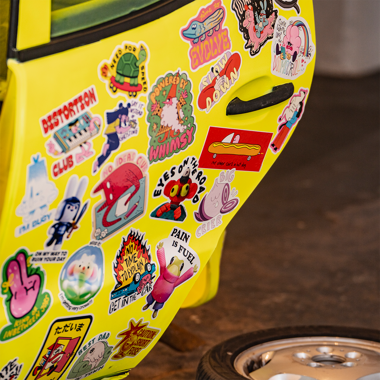 Yellow Mercedes body covered in bumper stickers in various shapes and sizes, with one door open.