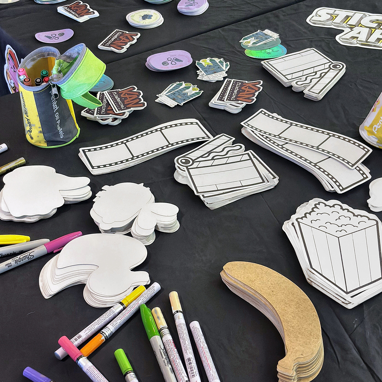 Stickertafel op het KAN Film Festival met blanco contourgesneden stickers in de vorm van popcorn, filmstroken en klapborden, kraftpapierstickers en paintmarkers