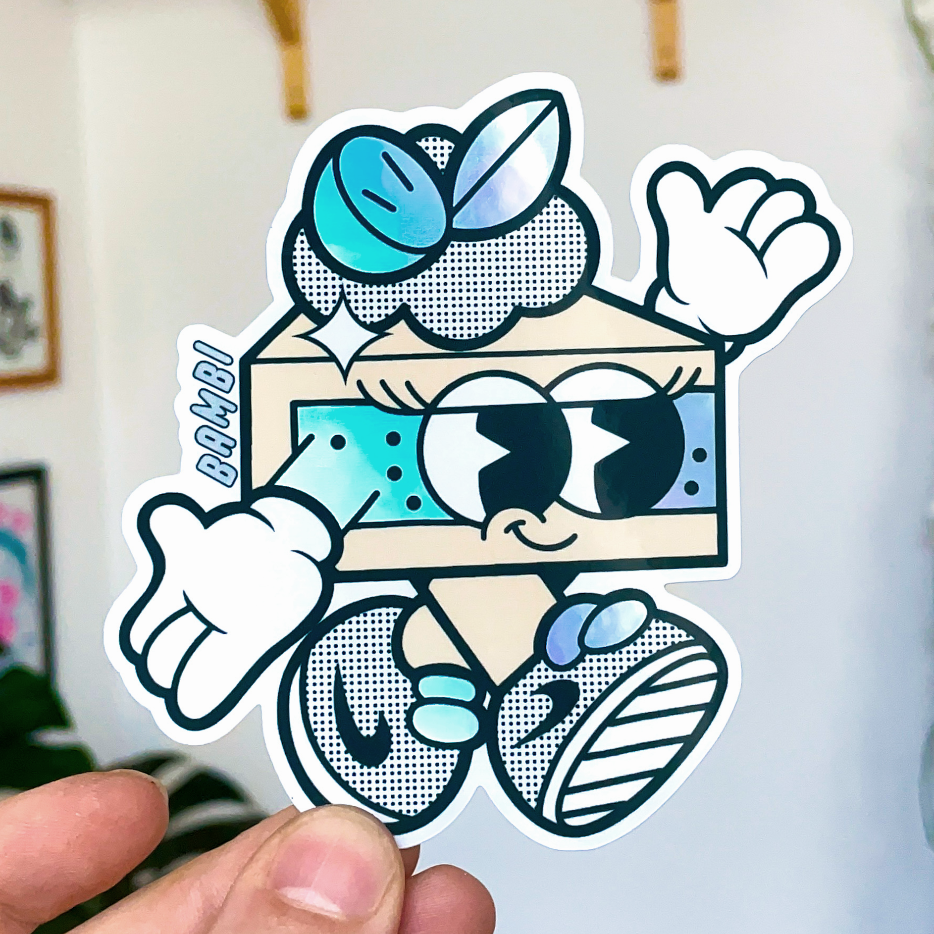 Cartoon holographic die cut sticker of a cake, big eyes, gloves, and sneakers.