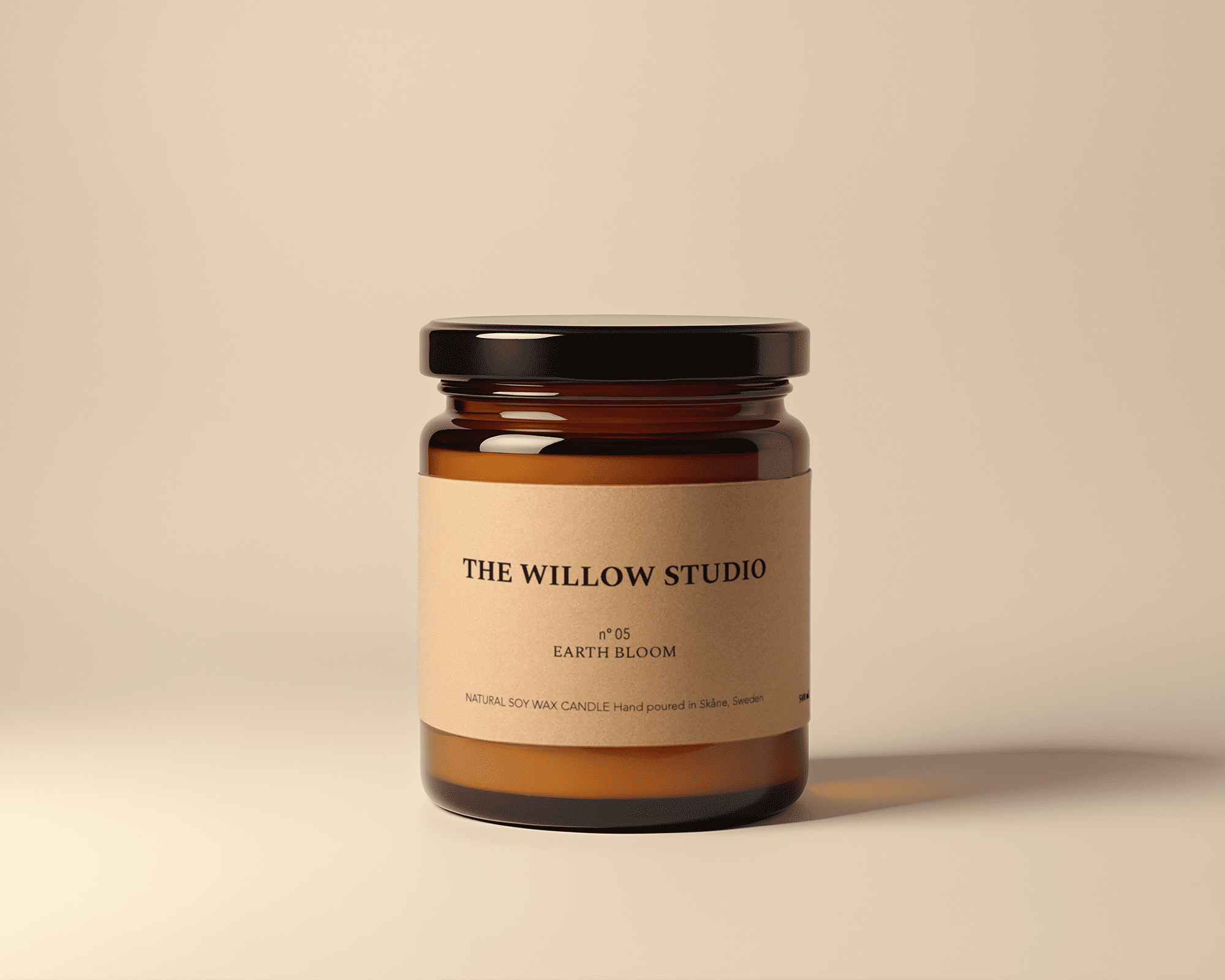 Brown glass jar candle with kraft label "The Willow Studio, Earth Bloom," on a soft beige background.