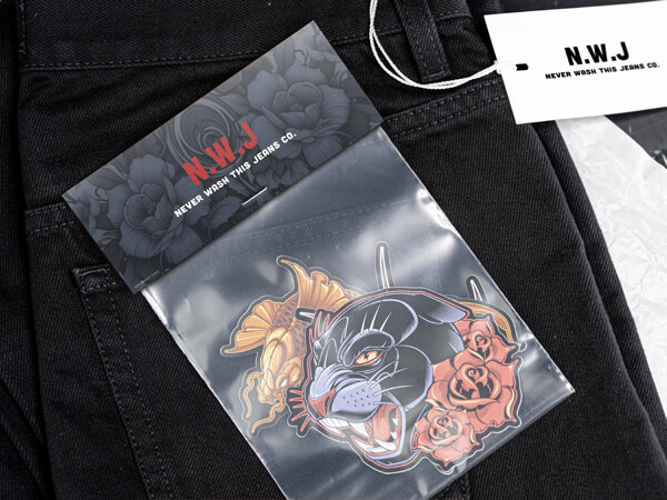 Contourgesneden sticker van een panter met rozen in een sticker pack met een headerkaart "N.W.J Never Wash This Jeans Co." op een zwarte jeans