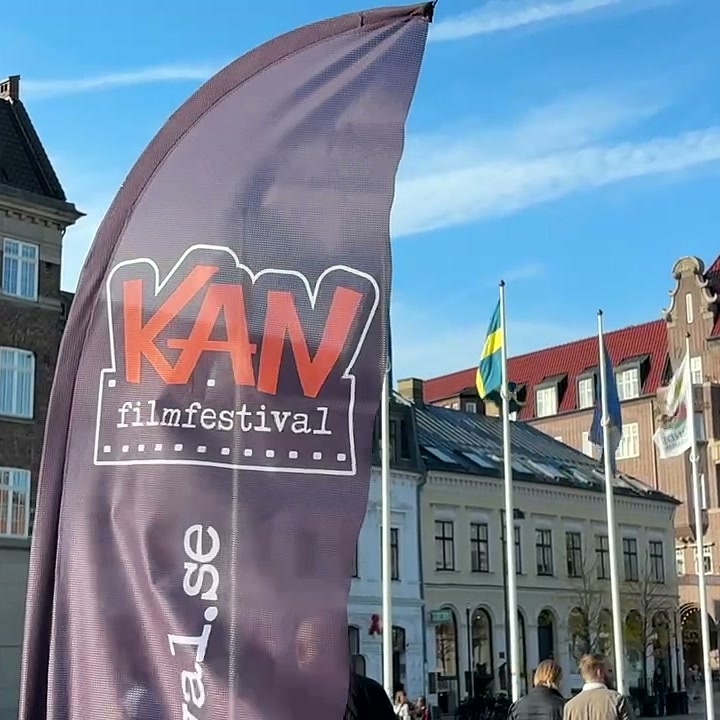 Beachflag van het KAN Film Festival voor historische gebouwen en vlaggen op een plein in Lund